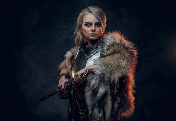 Fantasy žena rytíř na sobě cuirass a kožešiny, držící meč pochvu připraven k boji. Fantazie. Cosplayer jako Ciri z The Witcher. Studio fotografie — Stock fotografie