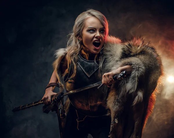Fantasy vrouw ridder draagt koord en vacht, houdt een zwaard vast en rent de strijd in met een woedende schreeuw. Cosplayer als Ciri uit The Witcher. — Stockfoto