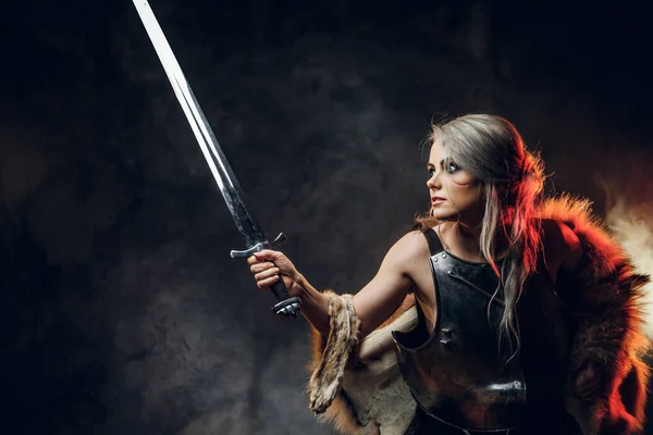 Portrait of a beautiful warrior woman holding a sword wearing steel cuirass and fur. Fantasy fashion. Cosplayer as Ciri from The Witcher. — Stock Photo, Image