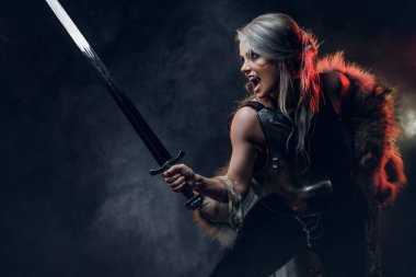 Kılıç tutan güzel savaşçı bir kadının portresi çelik kol ve kürk giyiyor. Fantezi modası. Ciri rolünde Cosplayer Cadıdan.