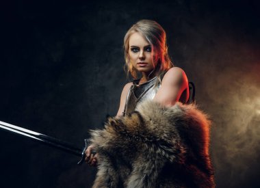 Kılıç tutan güzel savaşçı bir kadının portresi çelik kol ve kürk giyiyor. Fantezi modası. Ciri rolünde Cosplayer Cadıdan.