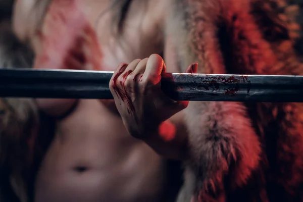 En naken kvinna med blodig hud som håller i ett långt svärd och poserar för en kamera. Närbild slöja på en hand som håller bladet av svärdet — Stockfoto