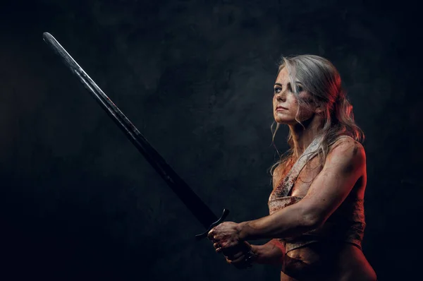 Naked Fantasy woman warrior wearing rag cloth stained with blood and mud in the heat of battle. Studio photo on a dark background. Cosplayer as Ciri from The Witcher