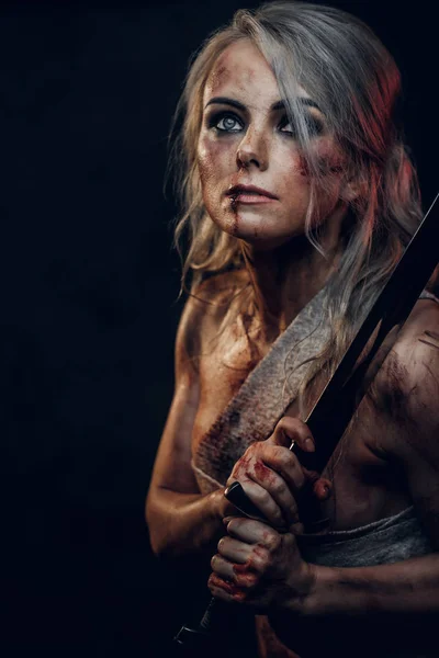 Donna guerriera Fantasy nuda che indossa un panno di straccio macchiato di sangue e fango nel calore della battaglia. Studio foto su uno sfondo scuro. Cosplayer come Ciri de La Strega — Foto Stock