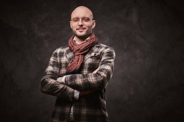 Succesful stylish businessman posing in a studio wearing checkered jacket, glasses and scarf