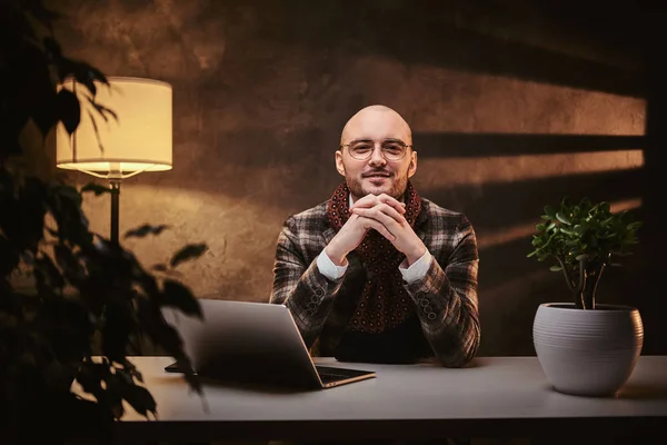 Καραφλός Ευρωπαίος καλοντυμένος χαμογελαστός επιχειρηματίας κάθεται στο γραφείο σε ένα τραπέζι με σημειωματάριο, φορώντας κομψό σακάκι και μαντήλι — Φωτογραφία Αρχείου