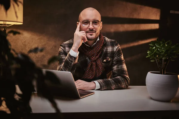Calvo europeo bien vestido hombre de negocios cansado sentado en la oficina en una mesa con cuaderno, con una chaqueta elegante y una bufanda —  Fotos de Stock