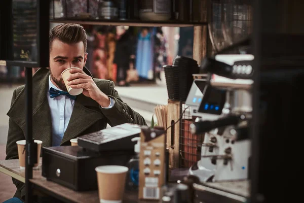 Cliente masculino de moda sentado al aire libre junto al equipo de fabricación de café en una cafetería móvil en un emporio de la ciudad — Foto de Stock