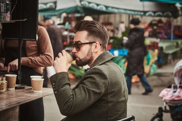 Elegante cliente masculino sentado al aire libre junto al equipo para hacer café en una cafetería móvil en un emporio de la ciudad — Foto de Stock