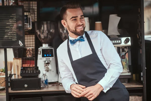 Elegant looking young man barista working in a mobile coffee shop outdoors