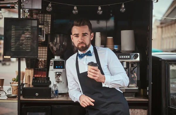 Handsome looking man barista working in a mobile coffee shop outdoors