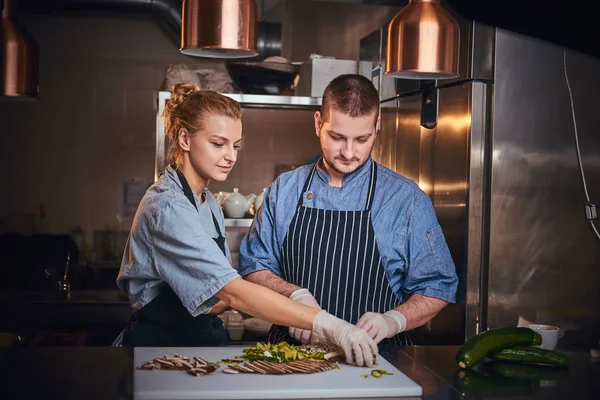Chefe masculino com assistente de pé em uma cozinha, preparando comida em um restaurante de luxo — Fotografia de Stock