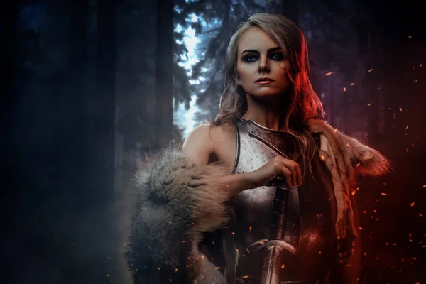 Portrait of a beautiful warrior woman holding a sword wearing steel cuirass and fur in night forest. Fantasy fashion. Cosplayer as Ciri from The Witcher. — Stock Fotó