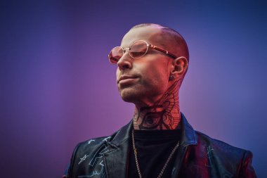 Kendine güvenen, kel, modaya uygun bir erkek model. Fotoshoot Vogue tarzı için bir stüdyoda poz veriyor. Şüpheli görünüyor.