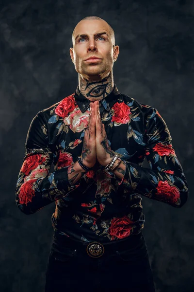 Elegante tatuato, calvo modello maschile alla moda in posa in uno studio per lo stile moda photoshoot mostrando un gesto di preghiera — Foto Stock