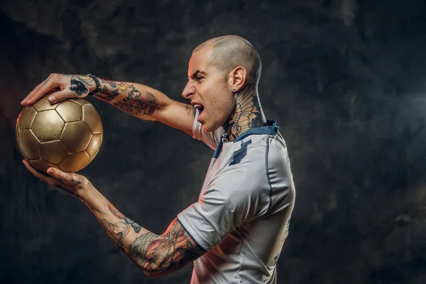 Rebellous tattooed, bald fashionable male soccer player posing in a studio for the photoshoot with a soccer ball — Stock Photo, Image