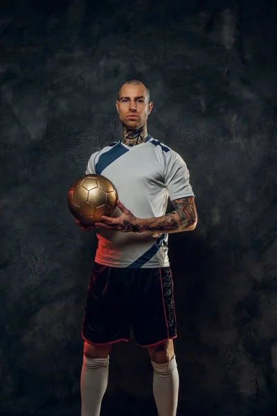 Hot tattooed, bald fashionable male soccer player posing in a studio for the photoshoot with a soccer ball Royalty Free Stock Photos