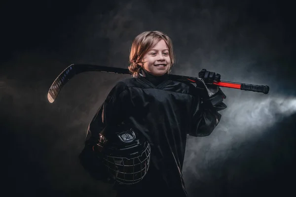 Young smiling hockey player posing in uniform for a photoshot in a studio — ストック写真