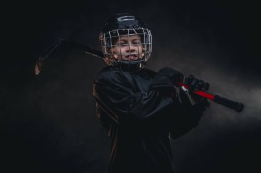 Young smiling hockey player posing in uniform for a photoshot in a studio