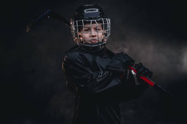 8-10 year old smiling hockey player posing in uniform for a photoshot in a studio