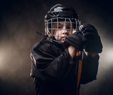 Young sad hockey player posing in uniform for a photoshot in a studio under the spotlights