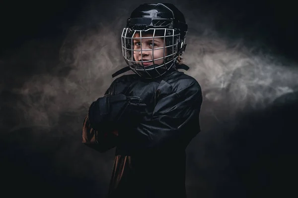 Giovane giocatore di hockey pazzo in posa in uniforme per una foto in uno studio buio sotto i riflettori — Foto Stock