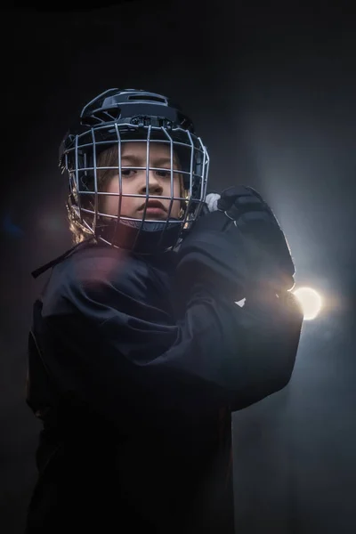 Giovane giocatore di hockey serio in posa in uniforme per una foto in uno studio sotto i riflettori — Foto Stock