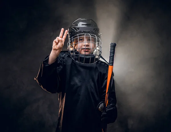 Giovane, 8-10 anni, sorridente giocatore di hockey in posa in uniforme per una foto in uno studio buio sotto i riflettori — Foto Stock