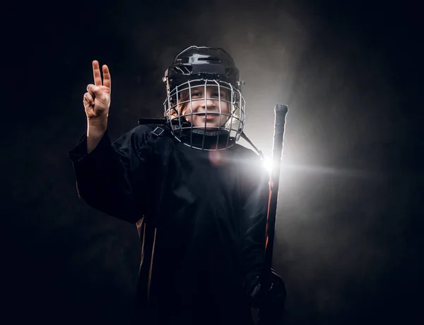 Young, 8-10 year old smiling hockey player posing in uniform for a photoshot in a dark studio under the spotlight — 스톡 사진