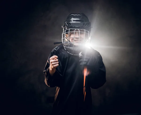 Young, 8-10 year old smiling hockey player posing in uniform for a photoshot in a dark studio under the spotlight — Zdjęcie stockowe