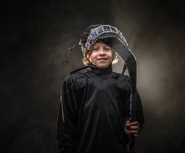 Young smiling hockey player posing in uniform for a photoshot in a studio — ストック写真