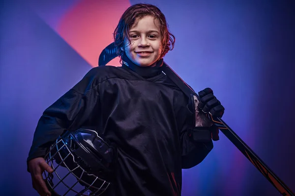 年轻快乐的曲棍球选手穿着制服在有霓虹灯的演播室拍照 — 图库照片