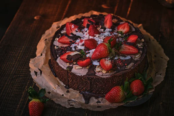 Vegan and delicious chocolate cake with strawberries, cocnut shovel and raspberry seeds, served on a paper serviette — Zdjęcie stockowe