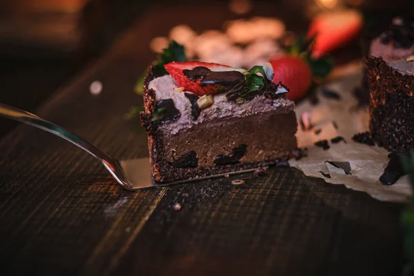 Vegan chocolate cake with strawberries, cocnut shovel and raspberry seeds, served on a paper serviette — Stockfoto