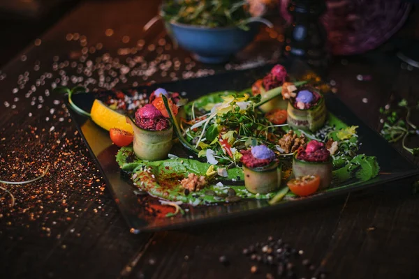 Haute cuisine vegetarian plate of appetizer rolls and a bowl of herbs served on a wooden table next to salt grinder in a restaurant — Stockfoto
