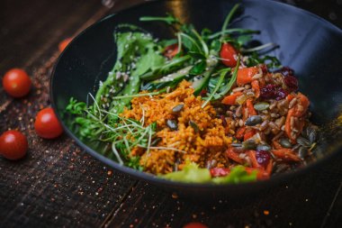 Nutritious vegetarian bowl of plov served on a wooden table decorated with spices in a dark soft light of a restaurant