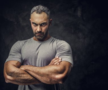 Adult caucasian muscular bodybuilder showing his muscles with arms crossed and looking on camera, portrait look