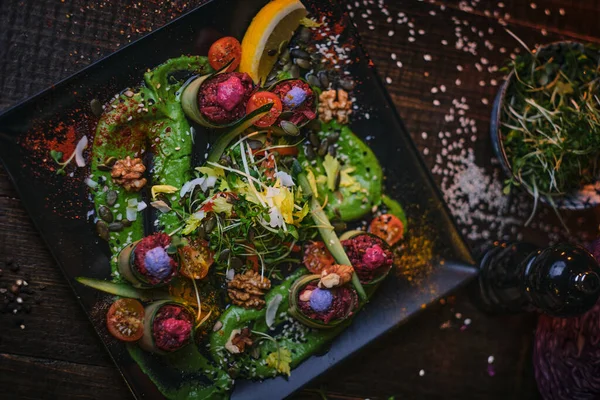 Luxe vegetarisch bord met voorgerecht broodjes en een kom kruiden geserveerd op een houten tafel naast zoutmolen in een restaurant — Stockfoto
