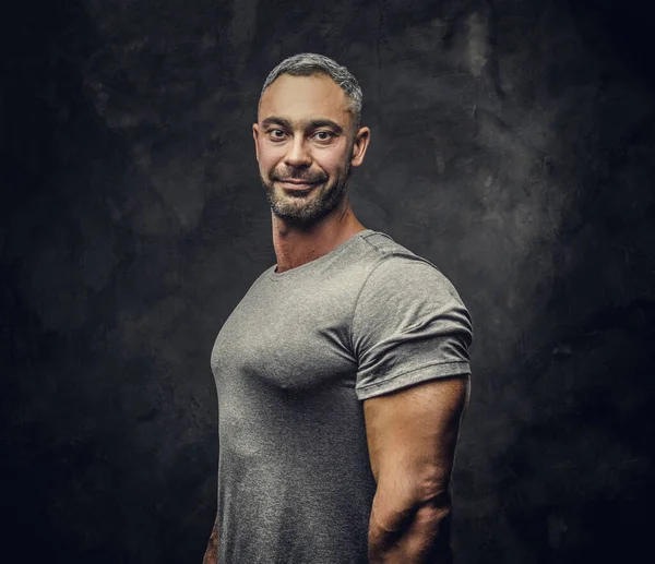 Adult caucasian muscular bodybuilder showing his muscles standing sideways and looking on camera, portrait look — ストック写真