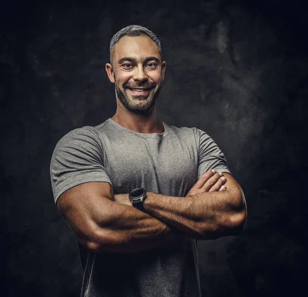 Adulto caucasiano musculoso fisiculturista mostrando seus músculos e olhando para a câmera no estúdio escuro, olhar retrato — Fotografia de Stock