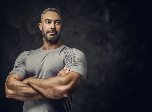 Взрослый тренер кавказских мускулистых бодибилдеров показывает свои мускулы со скрещенными руками и смотрит сбоку, портретный взгляд — стоковое фото