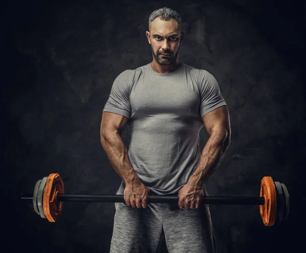 Sterk, volwassen, fit gespierde blanke man coach poseren voor een fotoshoot in een donkere studio onder de aandacht, met een sport gewichten — Stockfoto