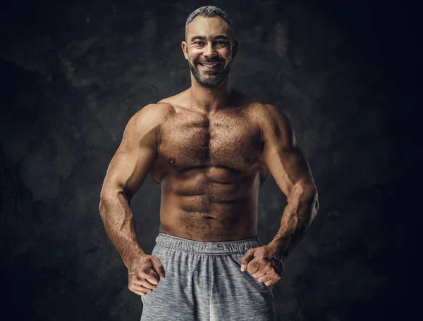 Adulto caucasiano musculoso fisiculturista mostrando seus músculos e olhando para a câmera, olhar retrato — Fotografia de Stock