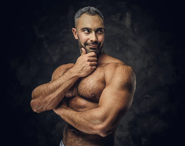 Взрослый кавказский культурист показывает свои мускулы и смотрит в сторону, думая: — стоковое фото