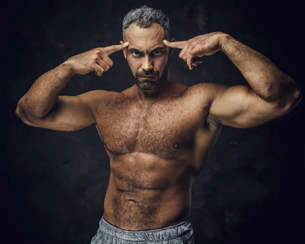 Adult athletic caucasian muscular bodybuilder coach showing his muscles and looking grumpy on camera, portrait look — Stockfoto