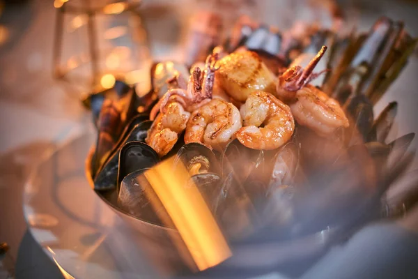 在餐馆里，一大碗烤虾和贻贝在金蜡烛旁边的石桌上 — 图库照片