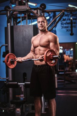 Athletic man with muscular body doing excersises with barbell in a gym
