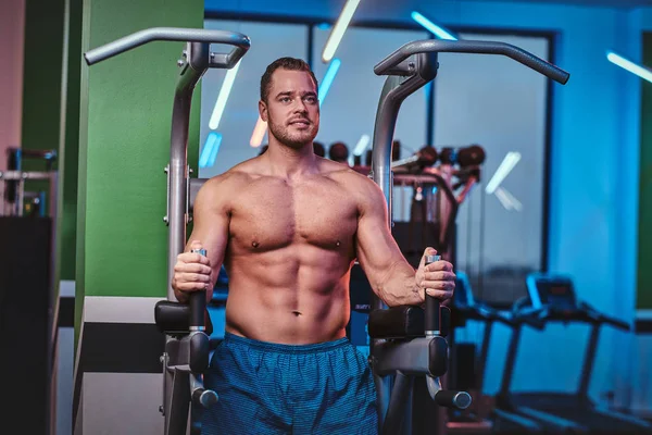 Culturista fuerte haciendo ejercicio en un bar paralelo en un moderno gimnasio — Foto de Stock