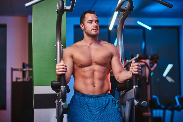 Strong bodybuilder doing excersise on a parallel bars in a modern fitness center — Zdjęcie stockowe