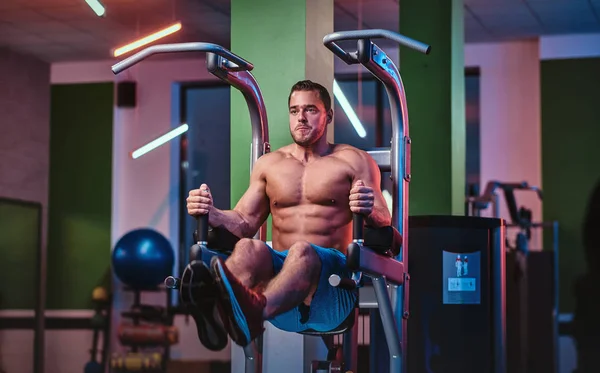 Strong bodybuilder doing excersise on a parallel bars in a modern fitness center — Stock fotografie